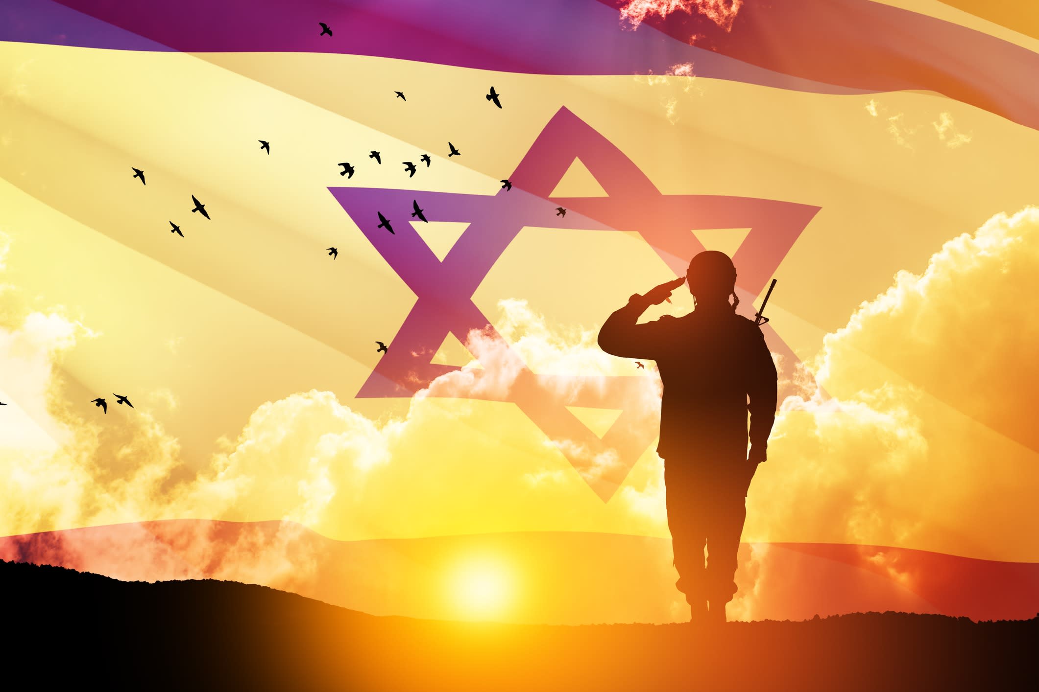 Silhouette of soldier saluting against the sunrise in the desert and Israel flag