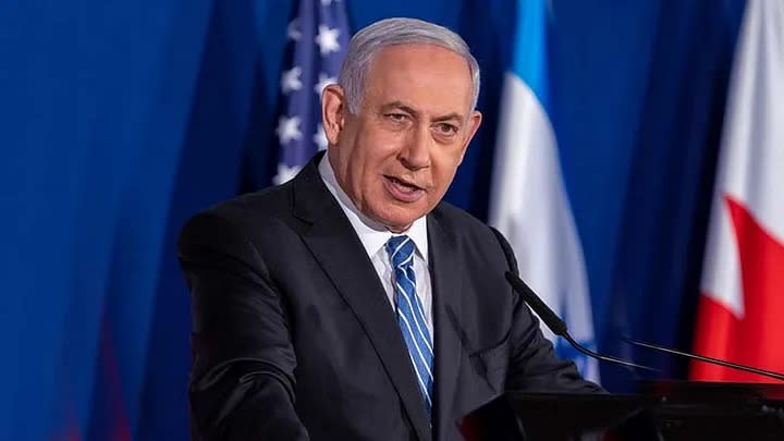 Prime Minister Binyamin (Bibi) Netanyahu speaking in front of flags